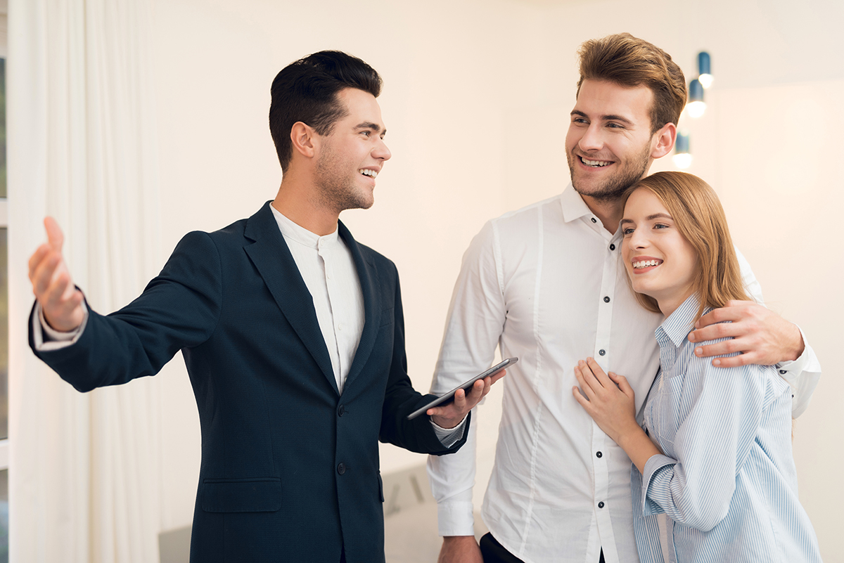 Realtor in a suit shows a new apartment to clients.